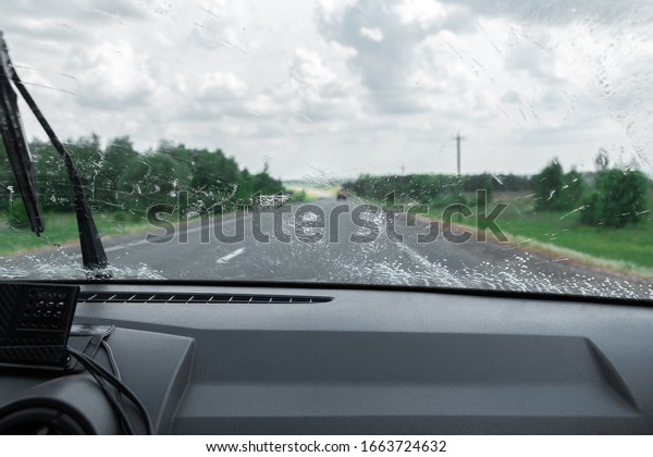 Cleaning the car\'s windshield with a windscreen\
wiper. Inside view