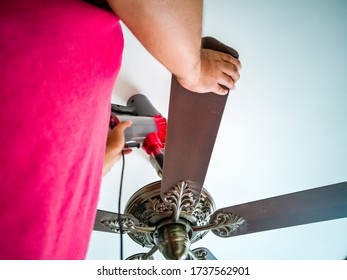 Cleaning The Ceiling Fan Using Vacuum Cleaner.