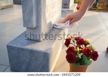 Cleaning the cemetery. A woman's hand washes the grey monument at the grave with a rag. Parents Saturday in Russia. business beautification of the graves.