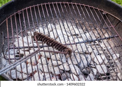 Cleaning A Charcoal Grill Grate With A Wire Brush.