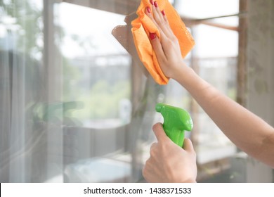 A Cleaning Company Cleans The Window Of Dirt. Housewife Polishes A House Window With A Window Cleaner And An Orange Rag.