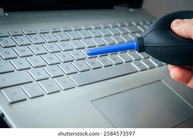 Cleaning computer with blower pump. Blowing debris from under the buttons on the keyboard with a special pear. using air bulb