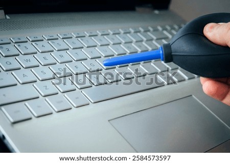 Cleaning computer with blower pump. Blowing debris from under the buttons on the keyboard with a special pear. using air bulb