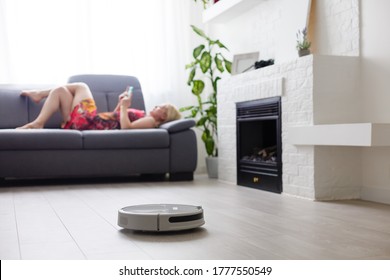 Cleaning Concept - Automatic Robotic Hoover Clean The Room While Woman Relaxing Close Up