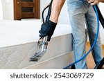 Cleaning concept. Cleaner cleans bed in the bedroom, close up. Virus prevention sanitizing inside. Process of deep furniture cleaning. Professionally chemical cleaning.