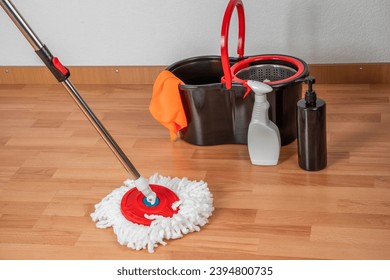 Concepto de limpieza, trapeo y balde. Productos de limpieza y hileras con detalles rojos en el suelo en un interior con parqué o parqué de madera, laminado