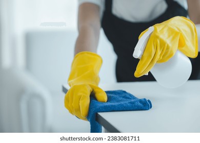 Cleaning desk surface in office with sanitizer spray, wear gloves and wipe the table with a towel, the housekeeper is cleaning the work desk for hygiene because of the Covid-19, cleaning idea. - Powered by Shutterstock