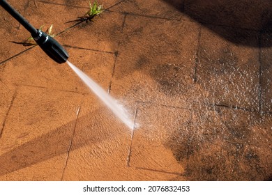 Cleaning dirty backyard paving tiles with pressure washer cleaner. Spring clean up