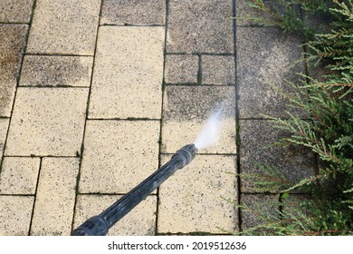 Cleaning Dirty Paving Stones In The Garden With A Pressure Washer.