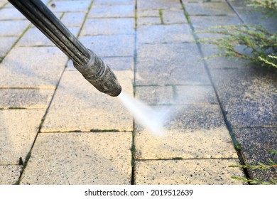 Cleaning Dirty Paving Stones In The Garden With A Pressure Washer.