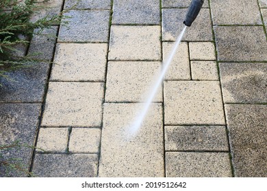 Cleaning Dirty Paving Stones In The Garden With A Pressure Washer.