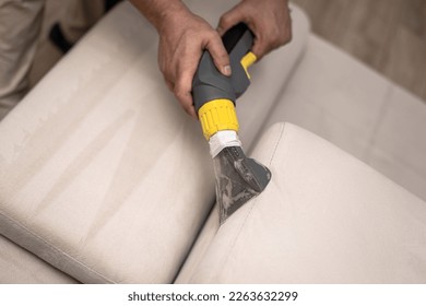 Cleaning a dirty sofa with a sofa washer. Close up of hands holding sofa cleaner. Professional sofa wash. Upholstery wash image