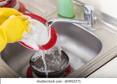 Cleaning Dishware Kitchen Sink Sponge Washing Dish. Close Up Of Female Hands In Yellow Protective Rubber Gloves Washing.