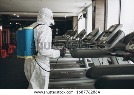 Cleaning and Disinfection in crowded places amid the coronavirus epidemic Gym cleaning and disinfection Infection prevention and control of epidemic. Protective suit and mask and spray bag Foto stock © 
