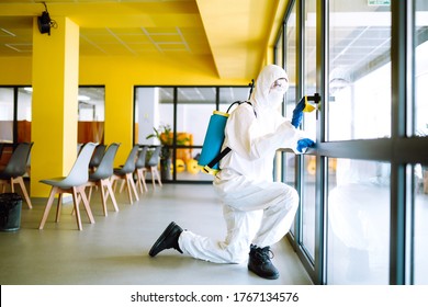 Cleaning and disinfection of office to prevent COVID-19. An disinfection in a protective suit and mask washes office furniture disinfectants. Prevention of spreading pneumonia virus with surfaces. - Powered by Shutterstock