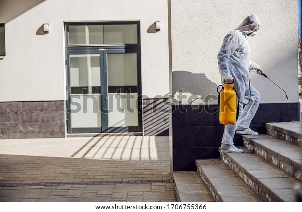 Cleaning and Disinfection outside around buildings,
the coronavirus epidemic. Professional teams for disinfection
efforts. Infection prevention and control of epidemic. Protective
suit and mask.