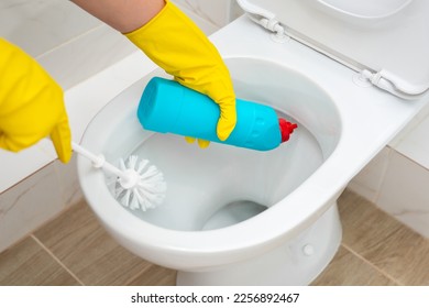 Cleaning and disinfection of toilets. Cleaner in yellow rubber gloves cleans the toilet with a brush. - Shutterstock ID 2256892467