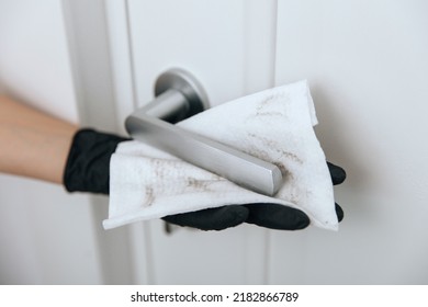 Cleaning Door Handle With Dirty Wipe In Black Gloves. Sanitize Surfaces Prevention In Hospital And Public Spaces Against Corona Virus. Woman Hand Using Towel For Cleaning Home Room Door Link.