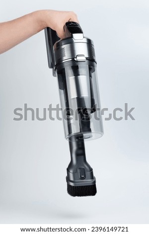 Cleaning dust witn mini wireless vacuum in hand isolated on white studio background