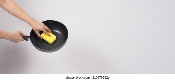 Cleaning Electric non stick pan. Hand on white background cleaning the non stick pan with handy dish washing sponge which yellow color on the soft side and green on hard side for hygiene after cook. - Powered by Shutterstock