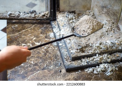 Cleaning The Fireplace. Ash And Charred Piece Of Wood Lying On The Blade With A Long Handle Closeup