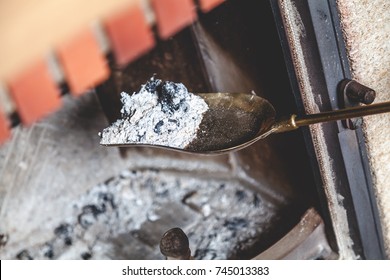 Cleaning The Fireplace. Ash And Charred Piece Of Wood Lying On The Blade With A Long Handle Closeup
