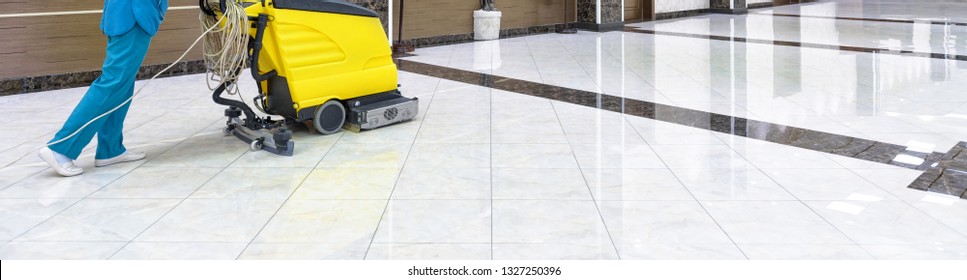 Cleaning floor with washing machine in office lobby or school. Panoramic view of corporate interior during cleaning with vacuum equipment. Clean shiny marble floor. Concept of commercial service.