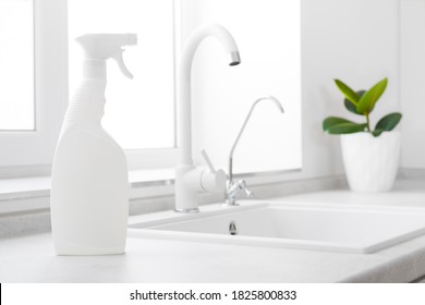 Cleaning fluid bottle on kitchen window and white sink background