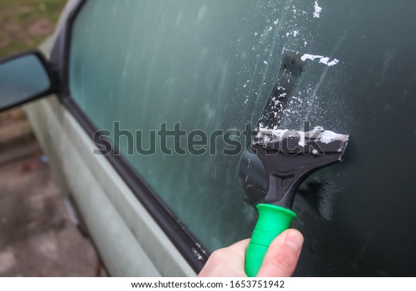 Cleaning a\
frozen car window with a metal\
scraper.