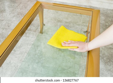 Cleaning A Glass Table With Yellow Cloth