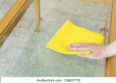 Cleaning A Glass Table With Yellow Cloth