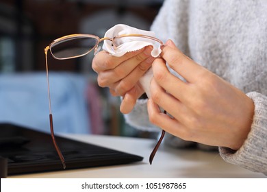 Cleaning glasses. The woman wipes her glasses with a cloth