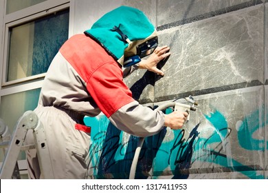 Cleaning graffiti from a building wall - Powered by Shutterstock