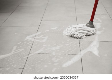 Cleaning grey tiled floor with string mop, space for text - Powered by Shutterstock