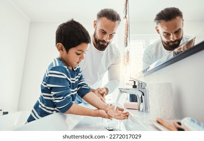 Cleaning hands, washing and father with boy in bathroom for hygiene, wellness and healthcare at home. Family, skincare and dad with child learning to wash with water, soap and disinfection by faucet - Powered by Shutterstock