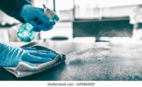 Reinigung des Haustischsanitisierenden Küchentisch mit Desinfektionssprühflasche Waschflächen mit Handtuch und Handschuhen. COVID-19 Präventivmaßnahmen im Inneren.