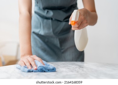 Cleaning hygiene, asian young maid woman, girl hand in using a water sprayer bottle to wipe clean, use blue rag wiping to dust on white marble table in restaurant. Housekeeping cleanup, cleaner.