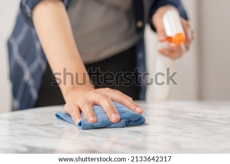 Cleaning hygiene, close up hand of young maid woman wearing protective gloves while cleaning on white marble table, use blue rag wiping to dust and spray in restaurant. Housekeeping cleanup, cleaner.