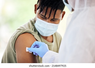 Cleaning The Injection Site. Cropped Shot Of An Unrecognizable Doctor Cleaning The Injection Site Of A Handsome Young Male Patient Before Administering The Covid 19 Vaccine.