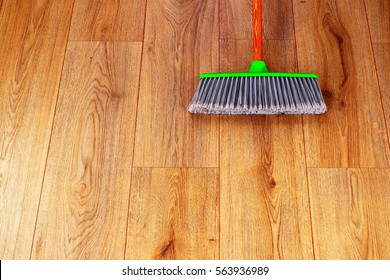 cleaning the interior wooden floor with green plastic broom - Powered by Shutterstock