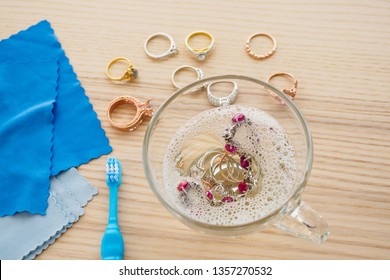 Cleaning Jewelry Diamond Ring With Glass Of Hot Water And Dishwashing Liquid On Wood Table Background