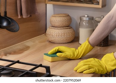 cleaning the kitchen with a sponge, hands in yellow protective rubber gloves wash the kitchen