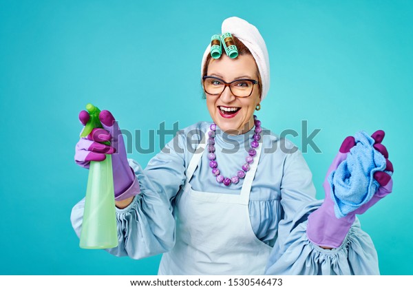 Cleaning Lady Fun. Elderly funny housewife fooling\
around with a broom. Full body isolated. Comical cleaning lady, old\
woman funky