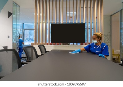 
Cleaning Lady With A Mask On Her Face Cleans A Table In An Office Photo