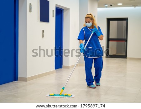 A cleaning lady with a mask on her face cleans the hallway Foto d'archivio © 
