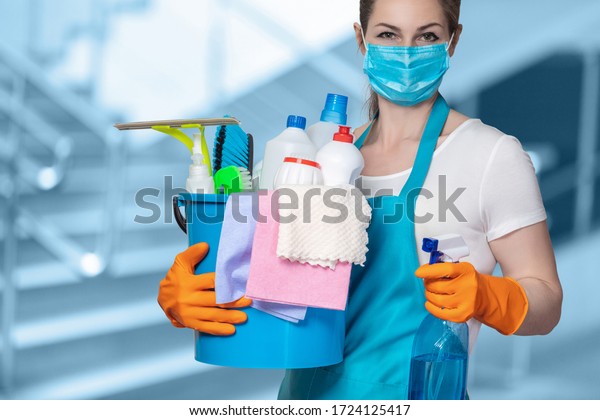 Cleaning lady with tool in cleaning in mask\
on a blurred\
background.