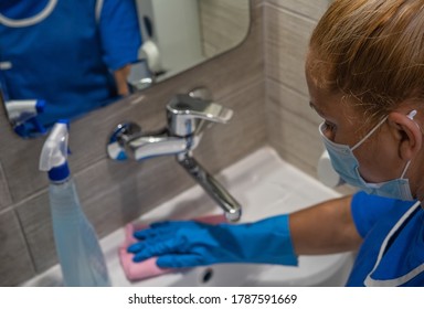 
A Cleaning Leady With Mask On Her Face Cleans The Washbasin