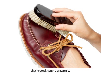 Cleaning leather shoes. Shoe care. Shoe brush and boat shoes in hands. Isolate on a white background.