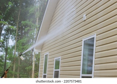Cleaning maintenance service for washing siding house and maintaining the home a high-pressure spray nozzle with soap cleaner and water - Shutterstock ID 2207573481