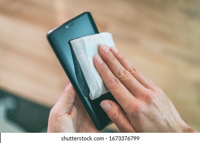 Cleaning mobile phone screen with disinfecting wet wipes for clean smartphone preventive wiping for COVID-19 Coronavirus outbreak contamination prevention. - Powered by Shutterstock